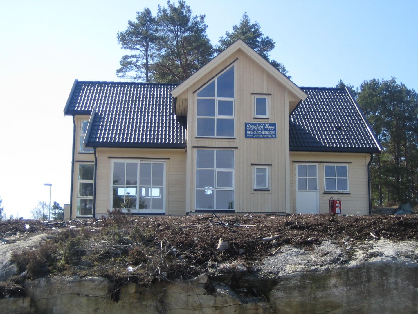 Ferdig hus med blått tak og store vinduer i gavlen