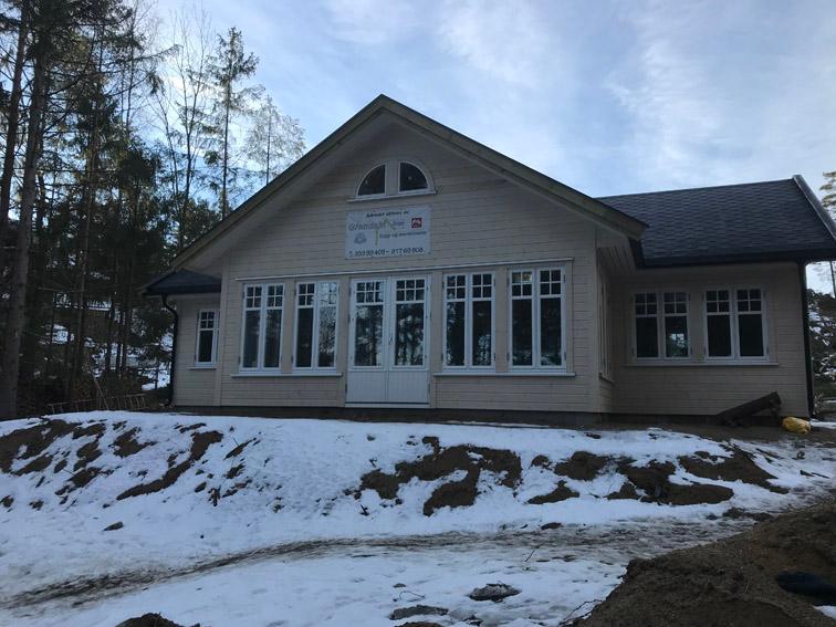 Ferdig hus med store sprossevinduer, snø på tomten