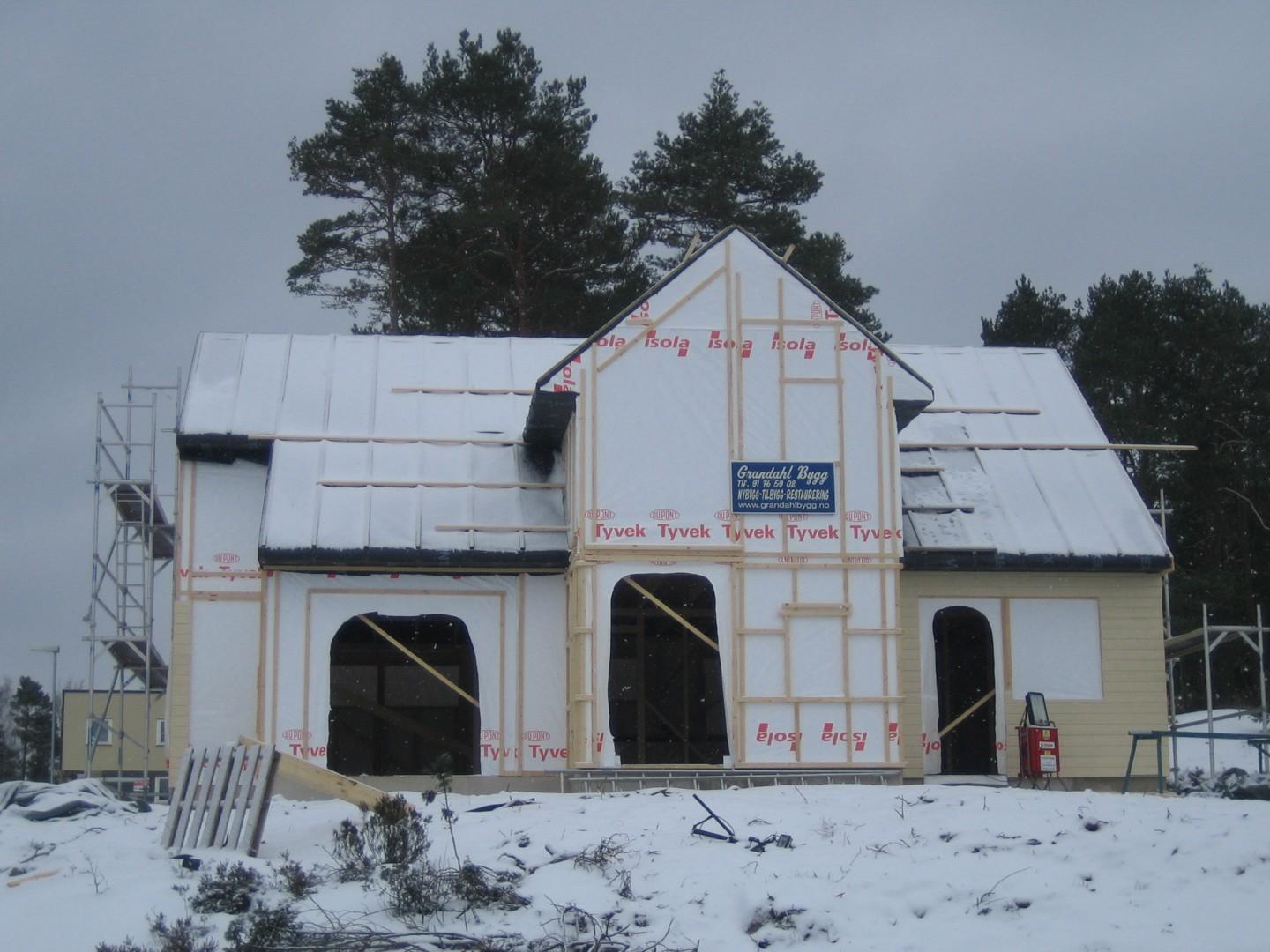 Hus med vindsperre og stillas, snø på bakken
